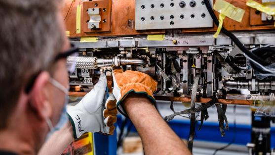 Technician Jason Ackley works on the first production model superconducting undulator magnet for the Advanced Photon Source Upgrade. These magnets operate at several different temperatures, the coldest around -450 degrees Fahrenheit. (Image by Jason Creps/Argonne National Laboratory.)